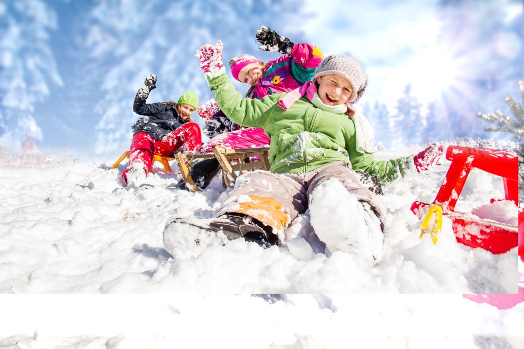 Vacances d’hiver des grandes familles- CSE : enfants en combinaison de ski jouant dans la neige pendant les vacances d’hiver